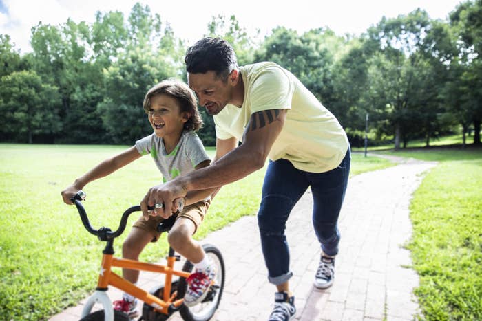 father teaching son to ride a bicycle