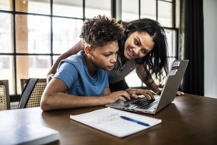 mother helping teenage son with homework in kitchen