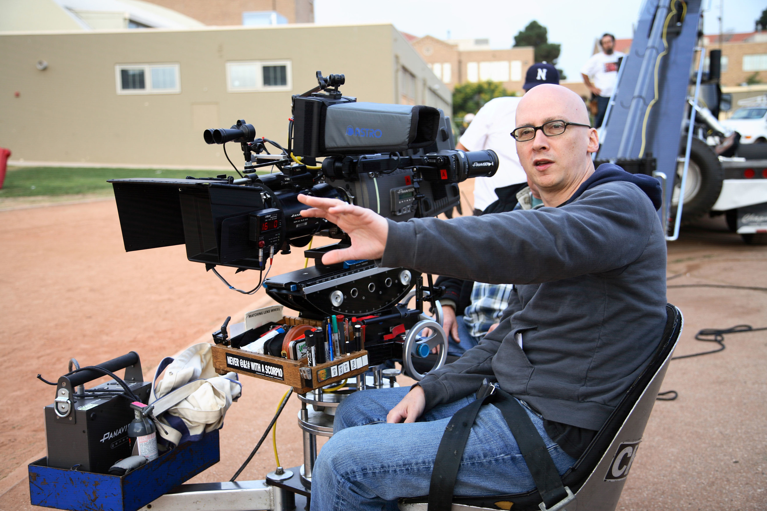 Greg sits in front of the camera on set