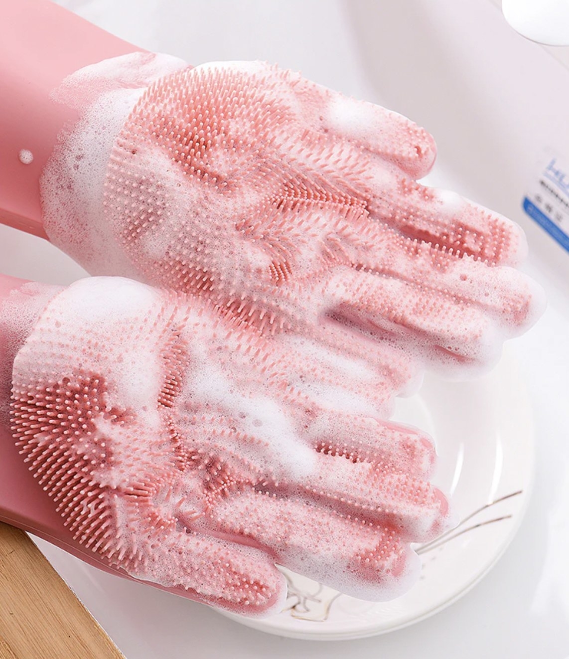 Someone wearing the pink gloves and showing the bristled palms covered in soapy water