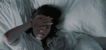 Woman rubbing eyes in bed