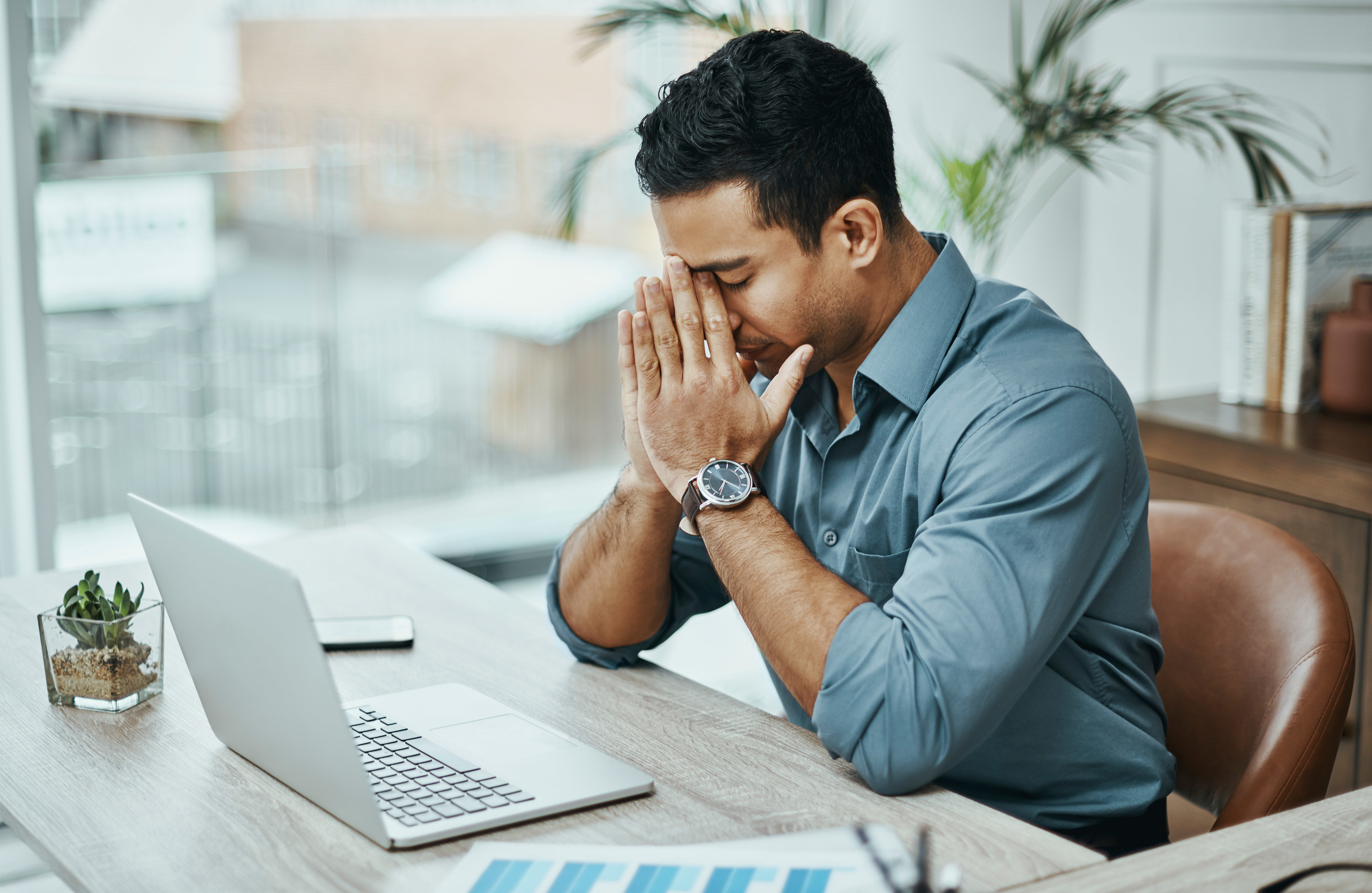 a stressed looking man sitting in front of a laptop