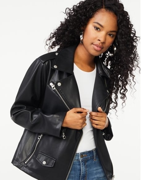 A model in a black leather jacket, a white t-shirt, and jeans