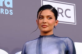 Kylie Jenner wears a fitted blue bodycon dress with her hair slicked back into a ponytail.