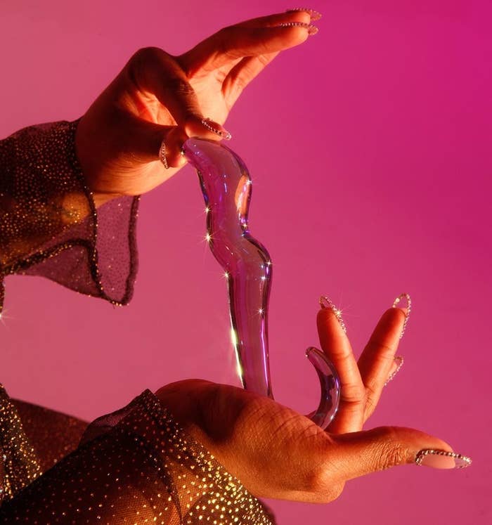 Model holding iridescent glass dildo