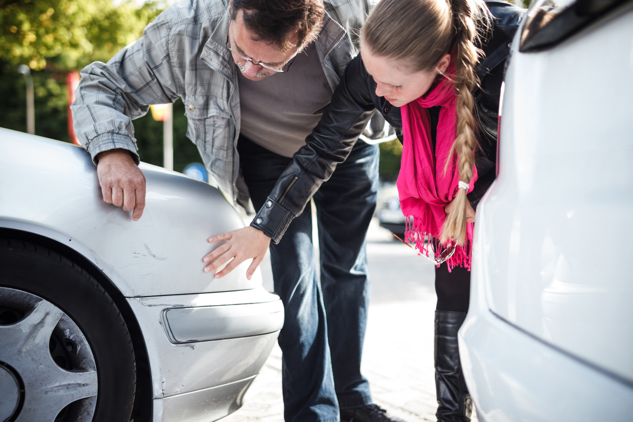 Man and woman inspecting car damage