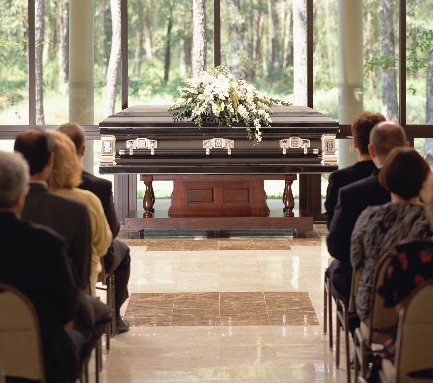 People sitting at a wake with a casket in front