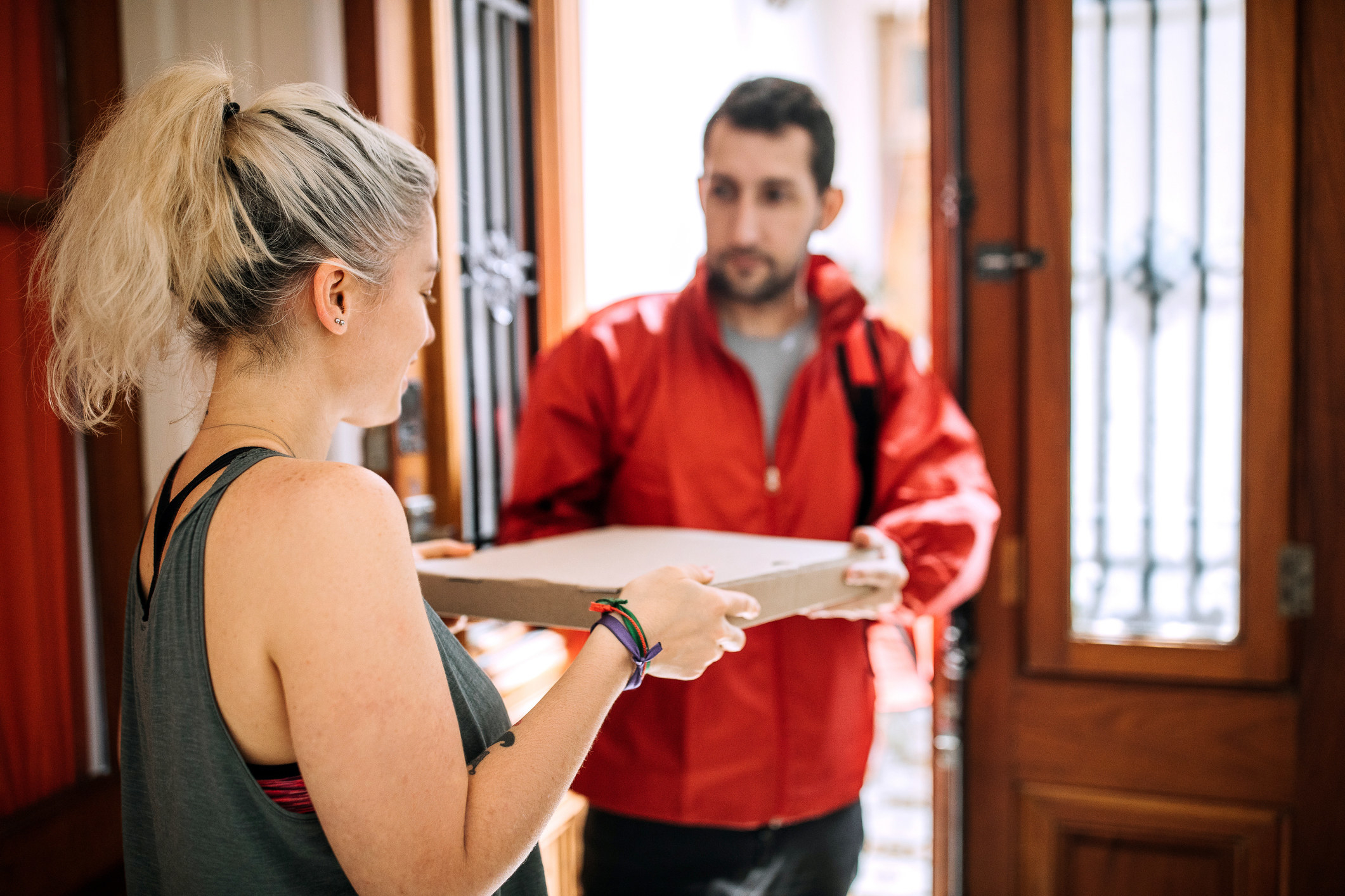 Man handing a woman a pizza pie in a doorway