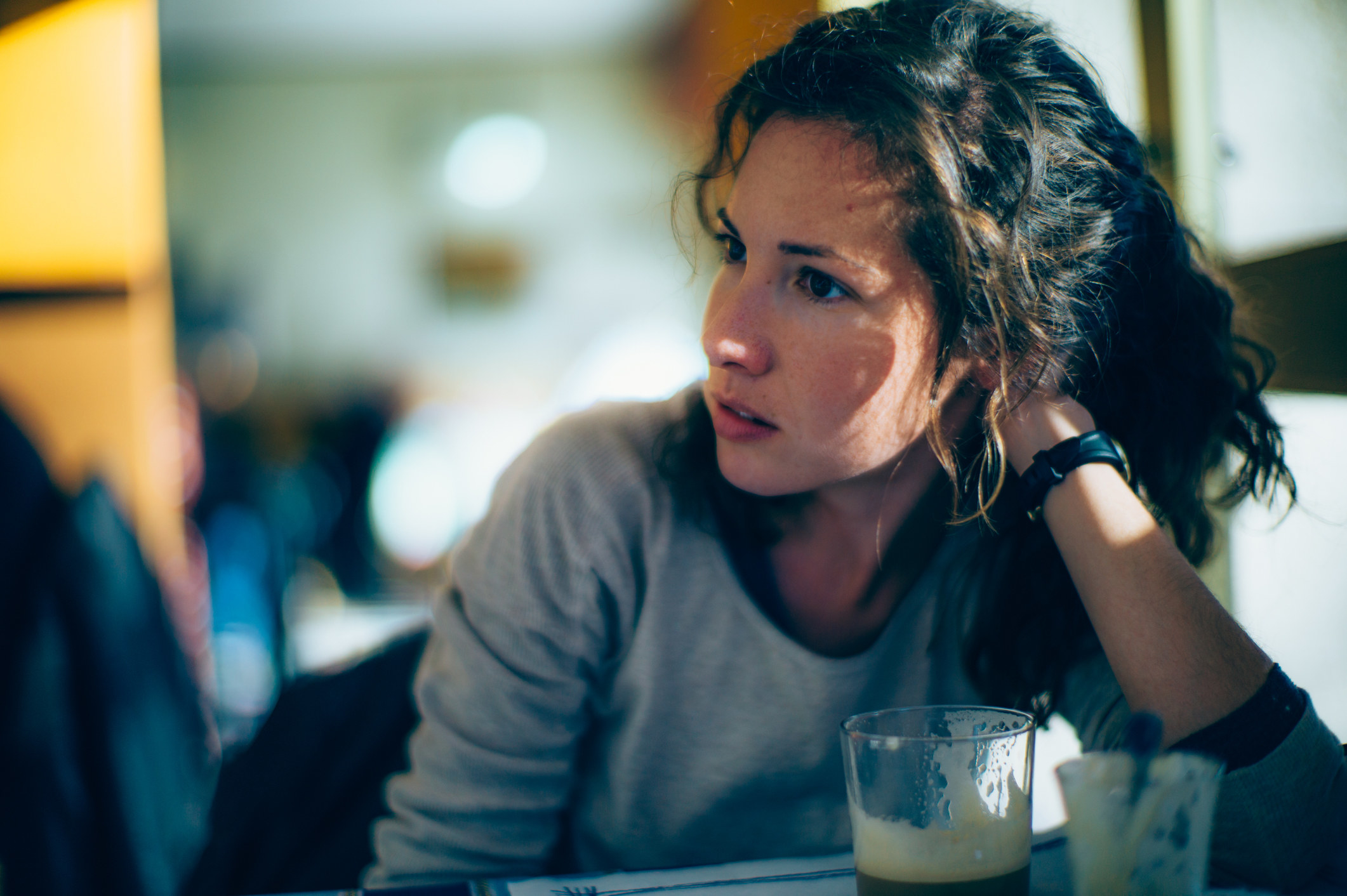 Woman sitting at a table resting her head on her hand and looking sideways