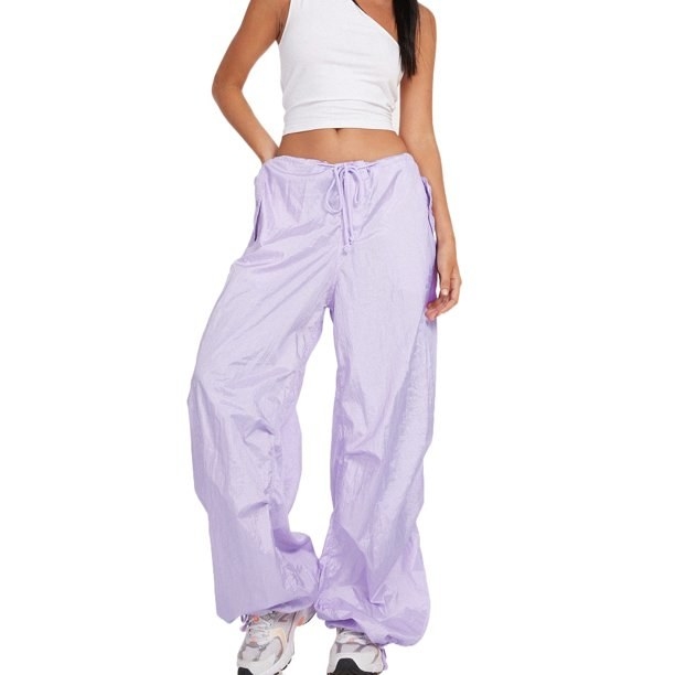 A model in a one-shoulder crop top, oversized lilac joggers, and sneakers