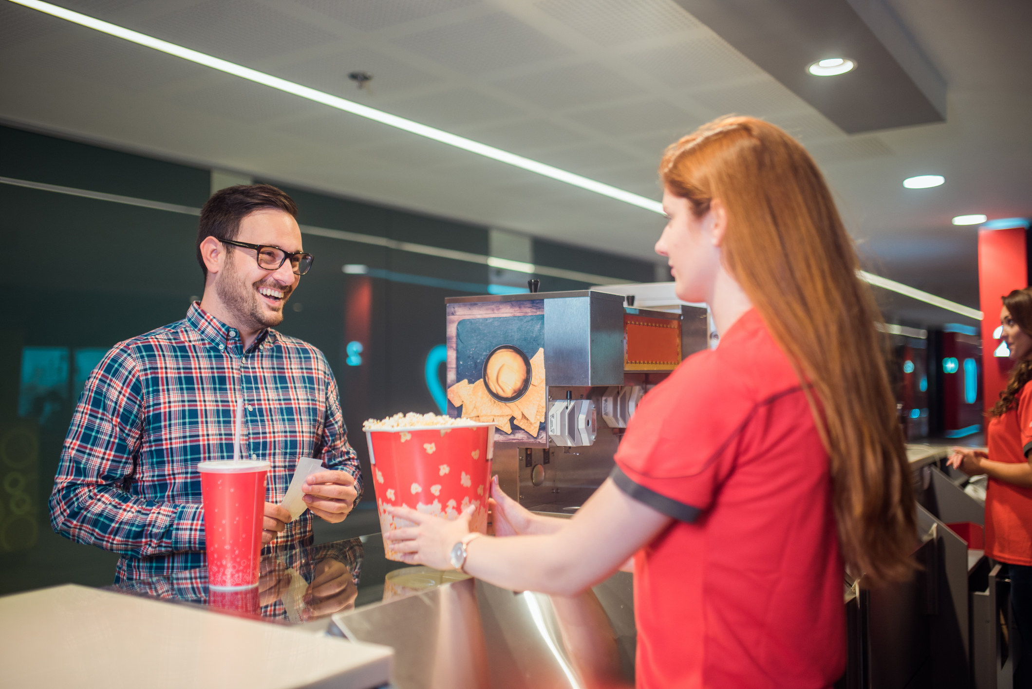 Man buying popcorn in a movie theater and smiling at the female concession worker