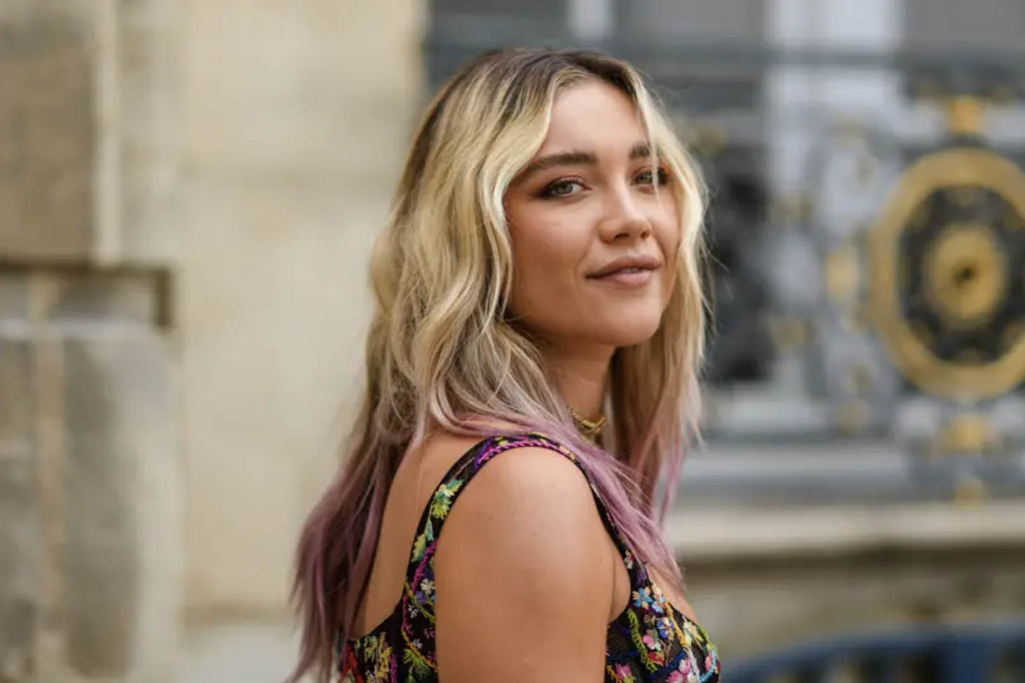 Florence Pugh has pink ombre hair and looks at the camera