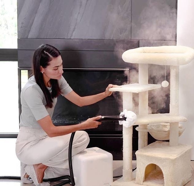 a person steam cleaning their fabric cat tower