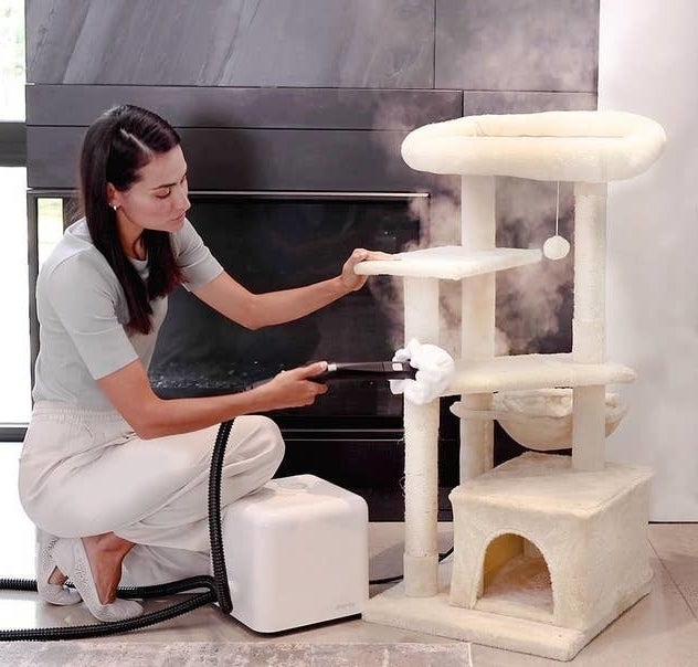 a person steam cleaning their fabric cat tower