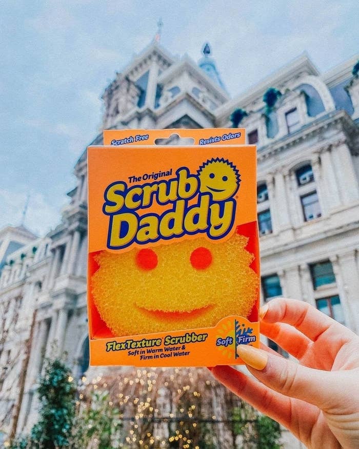 a person holding a scrub daddy sponge in its package outdoors