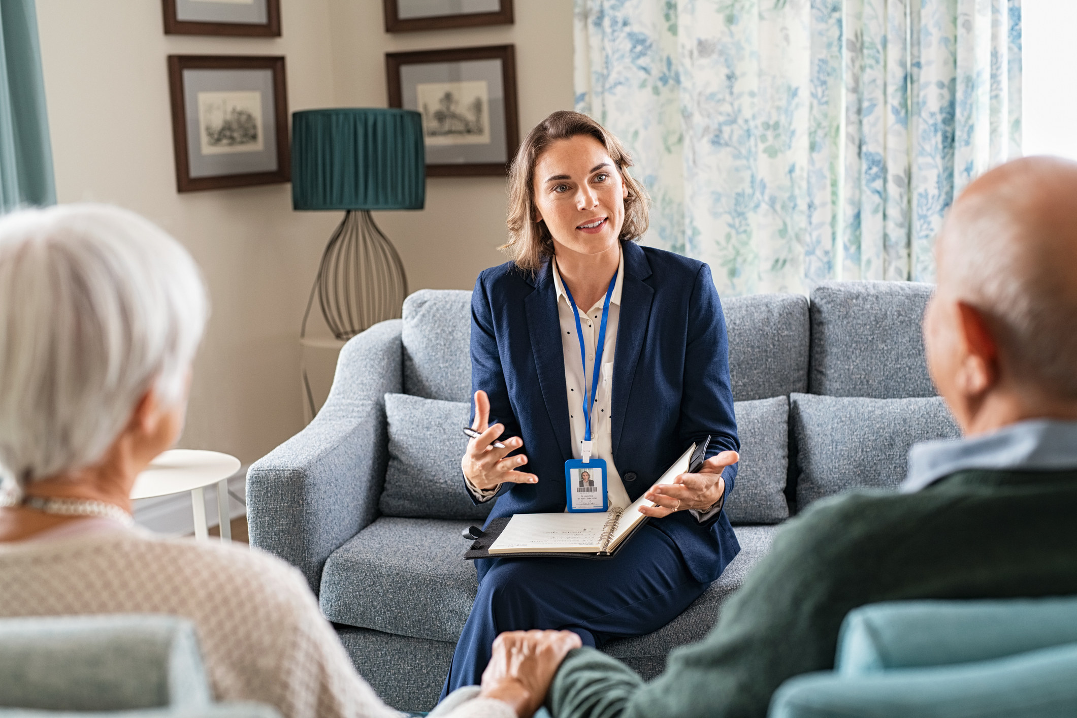 Woman sitting on a couch and speaking to two older people