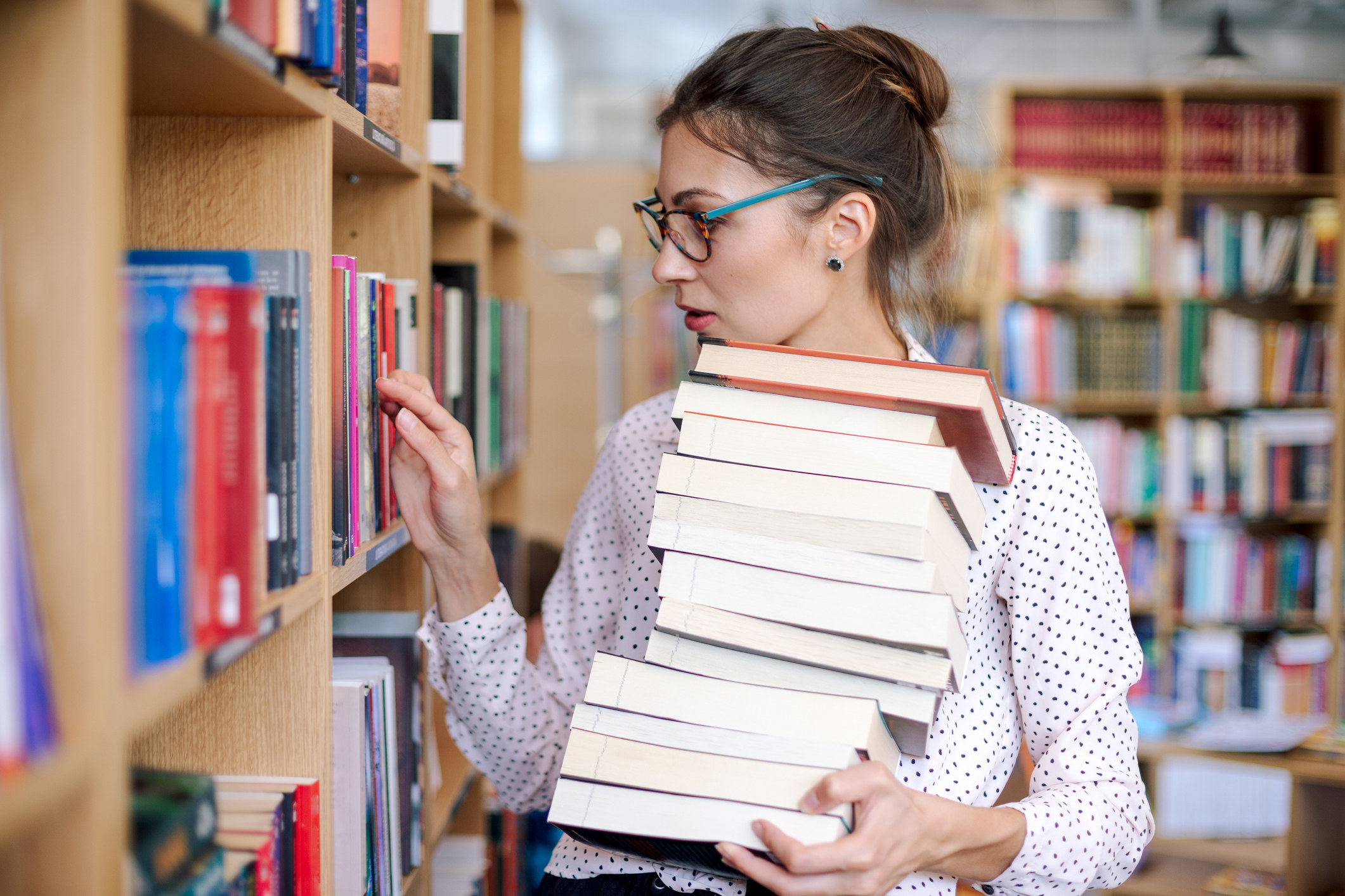A person in a library holding a stack of books