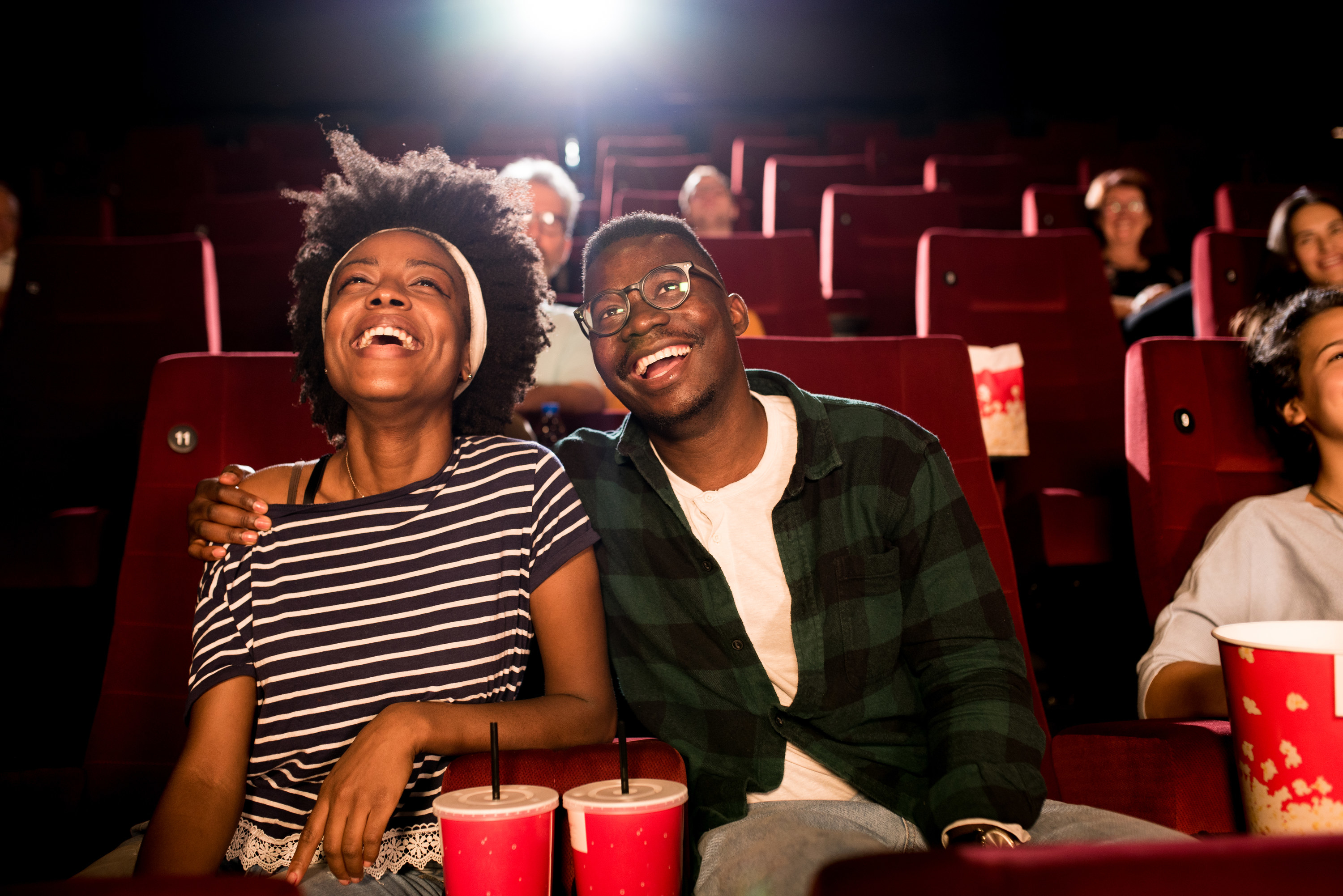 A couple sitting in a movie theater and laughing