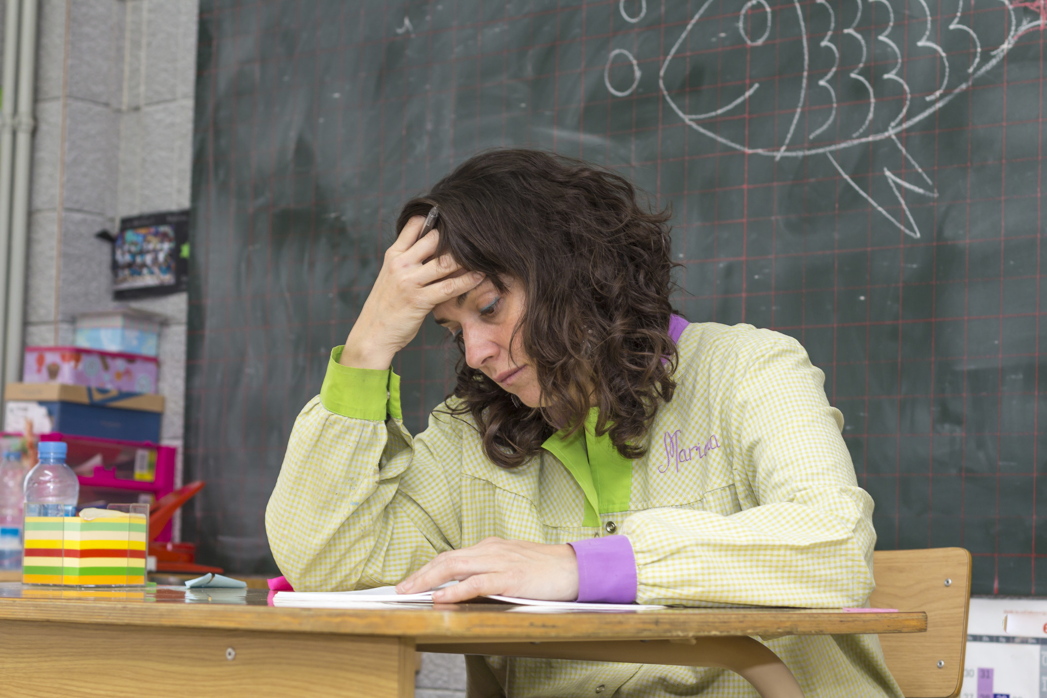 A teacher sitting at her desk and resting her head on her hand