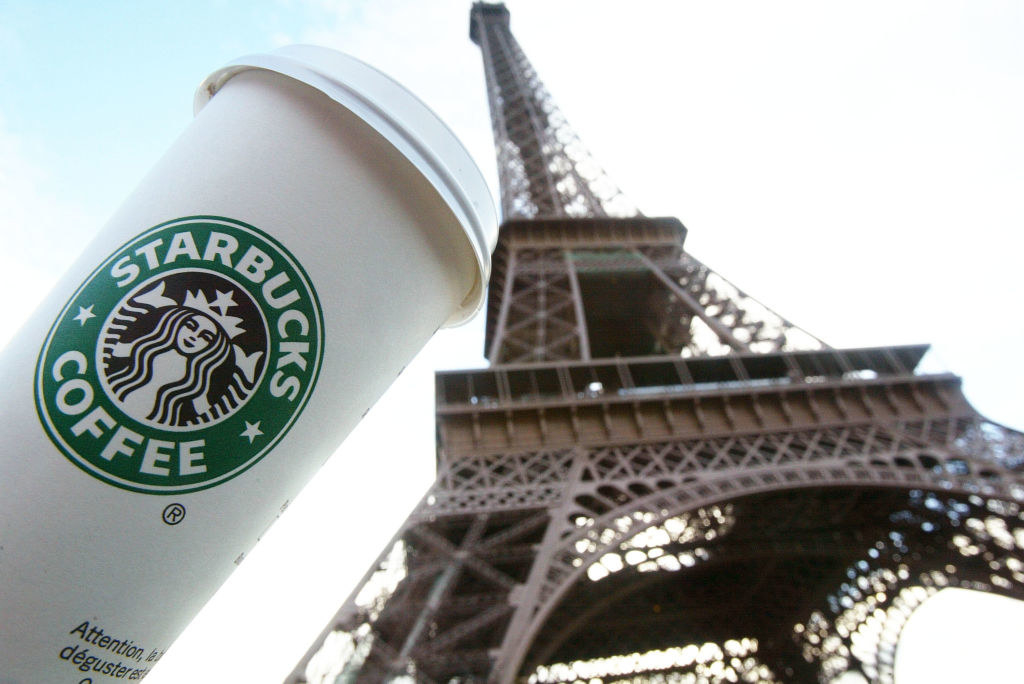 A Starbucks coffee cup next to the Eiffel tower.