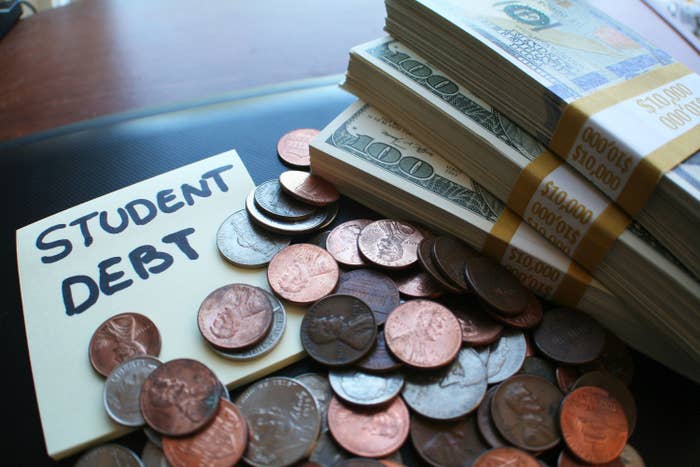 A note with &quot;Student debt&quot; on it next to coins and stacks of $100 bills