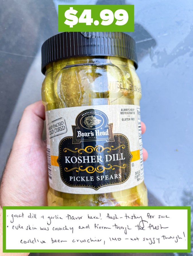 A hand holding a jar of Boar&#x27;s Head Kosher Dill pickles with a handwritten review note attached