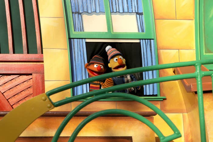 Two puppets wearing striped beanies stand at a window on structure on a parade float