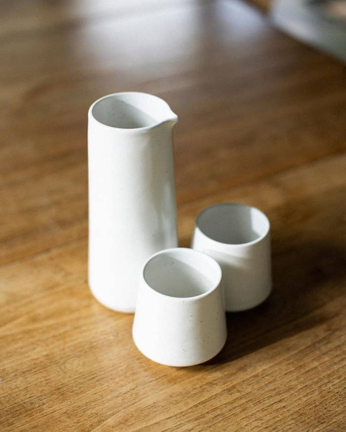 a handmade stoneware water carafe next to two matching cups