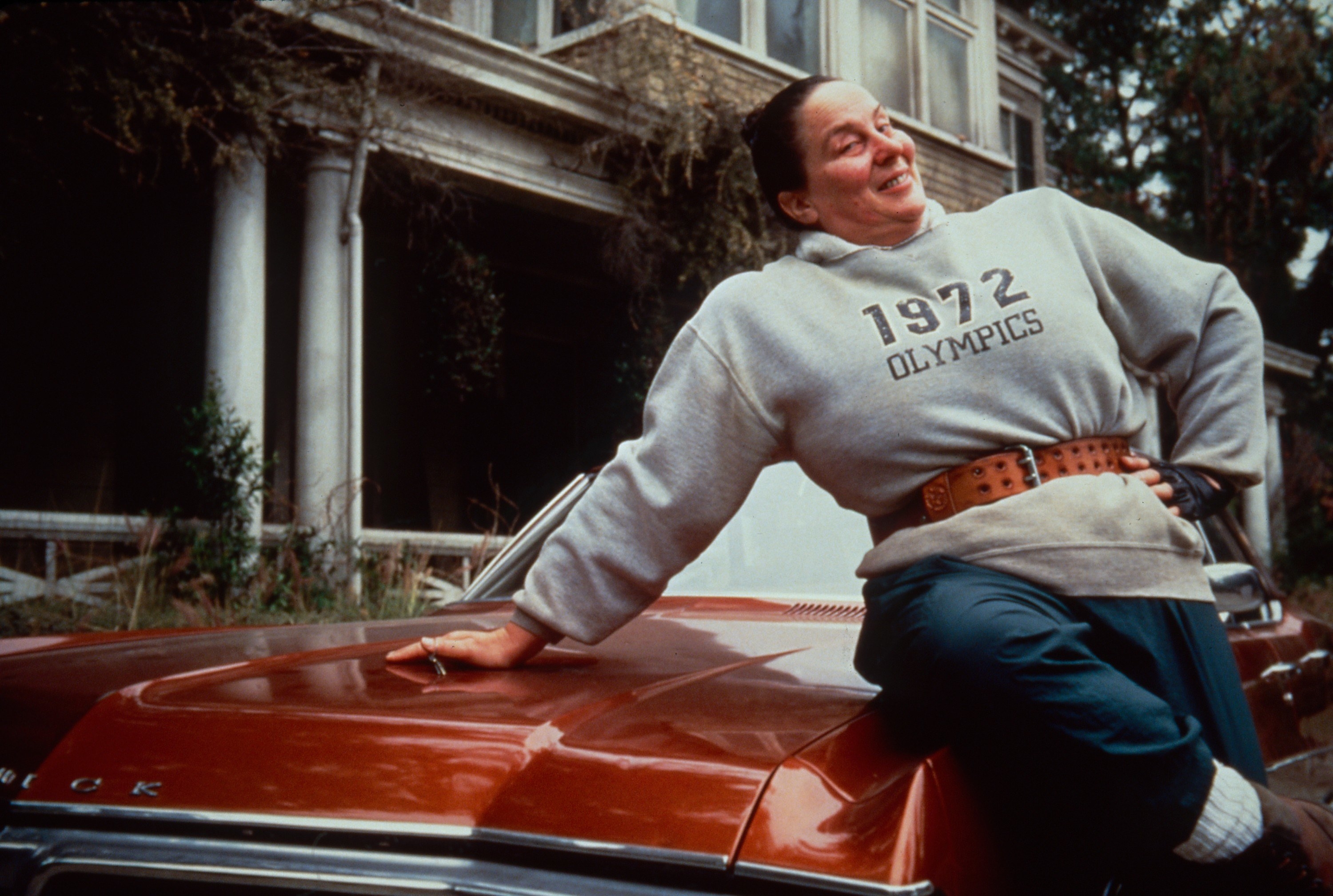 Pam as Trunchbull leaning against a car