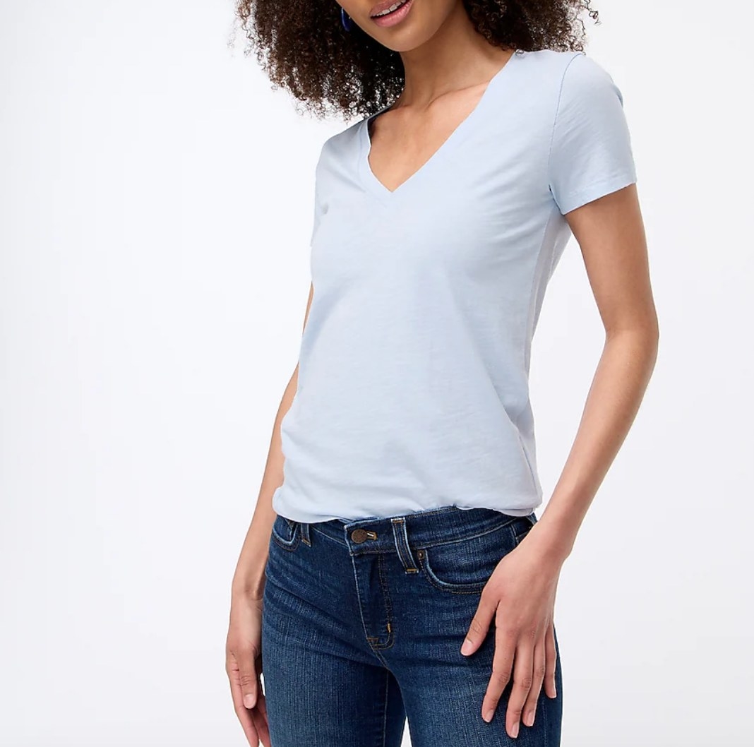 Model wearing light blue v-neck tee with dark wash jeans