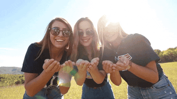 a group of girls blowing confetti into the camera
