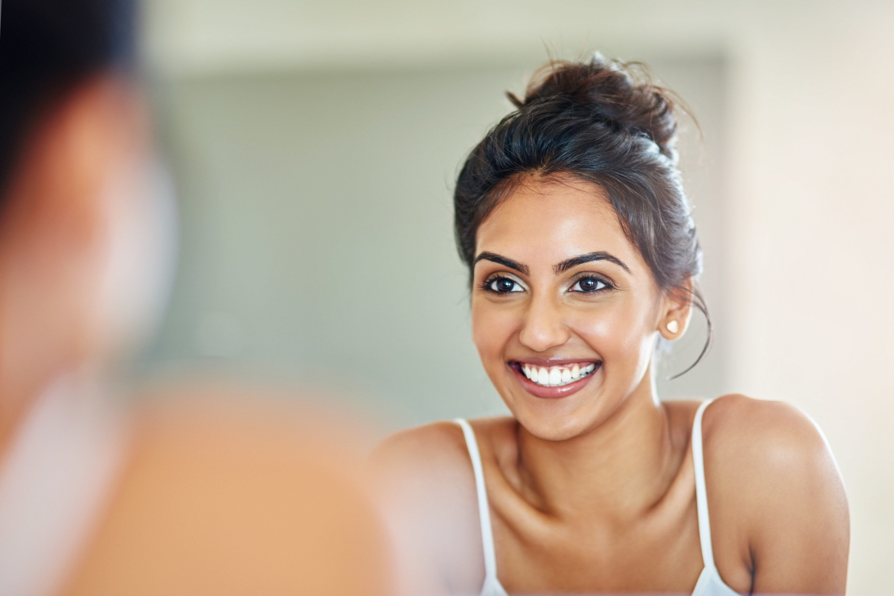 A woman looks at herself in the mirror and smiles