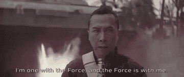 Chirrut Îmwe walking away from explosions and repeating his mantra that the Force is with him