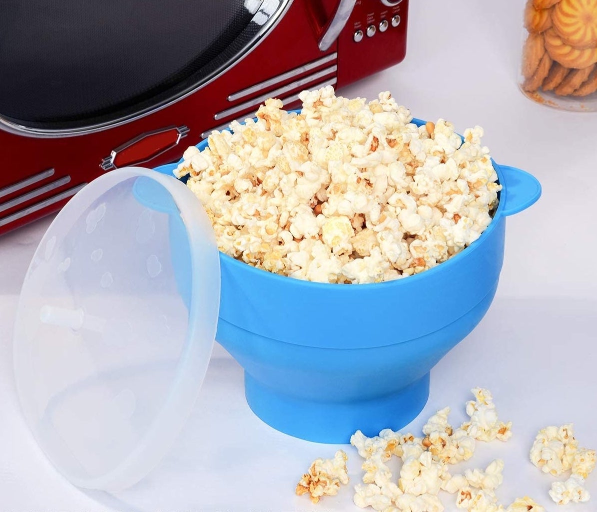 the bowl full of popcorn in front of a microwave