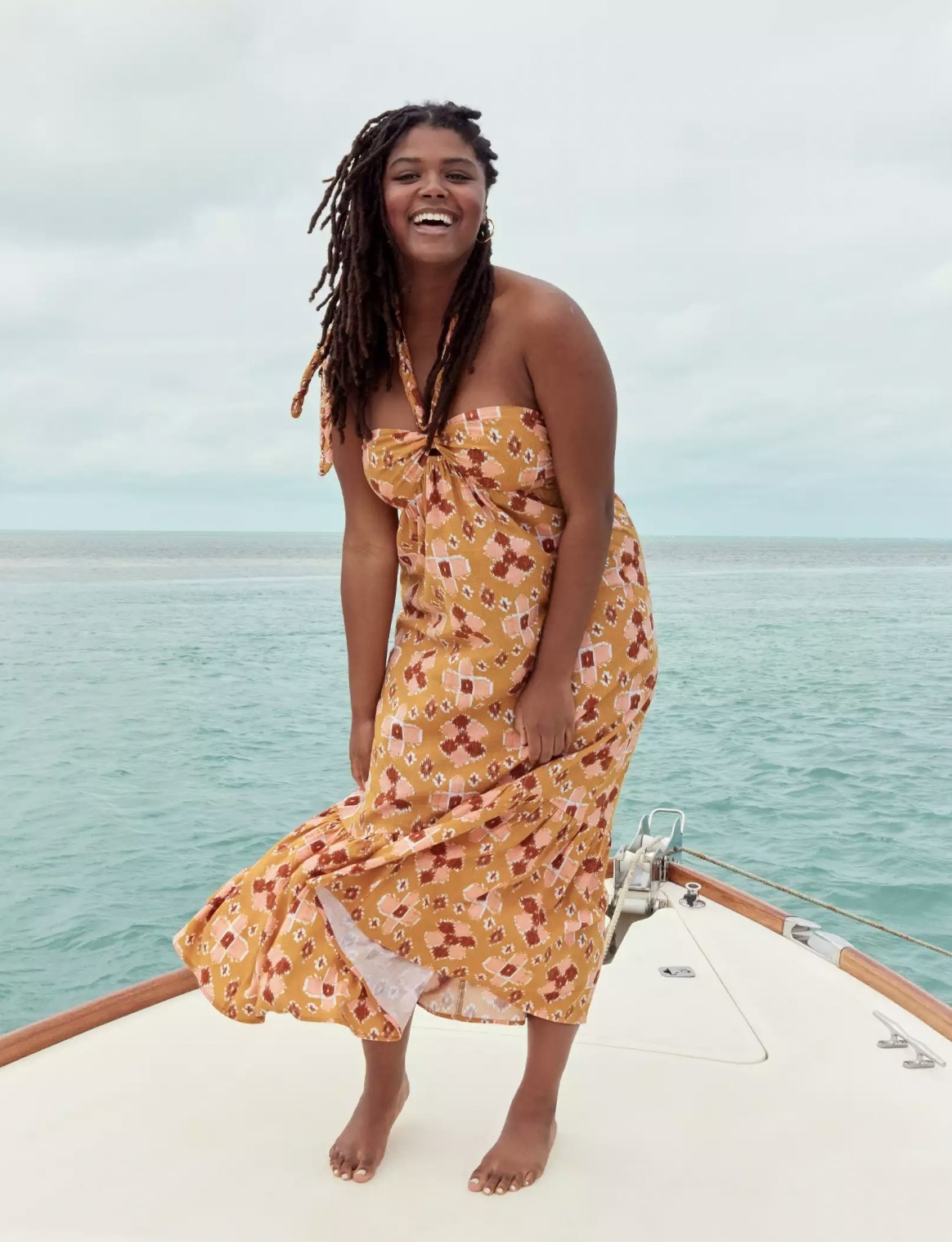 Model standing on bow of boat in the printed dress