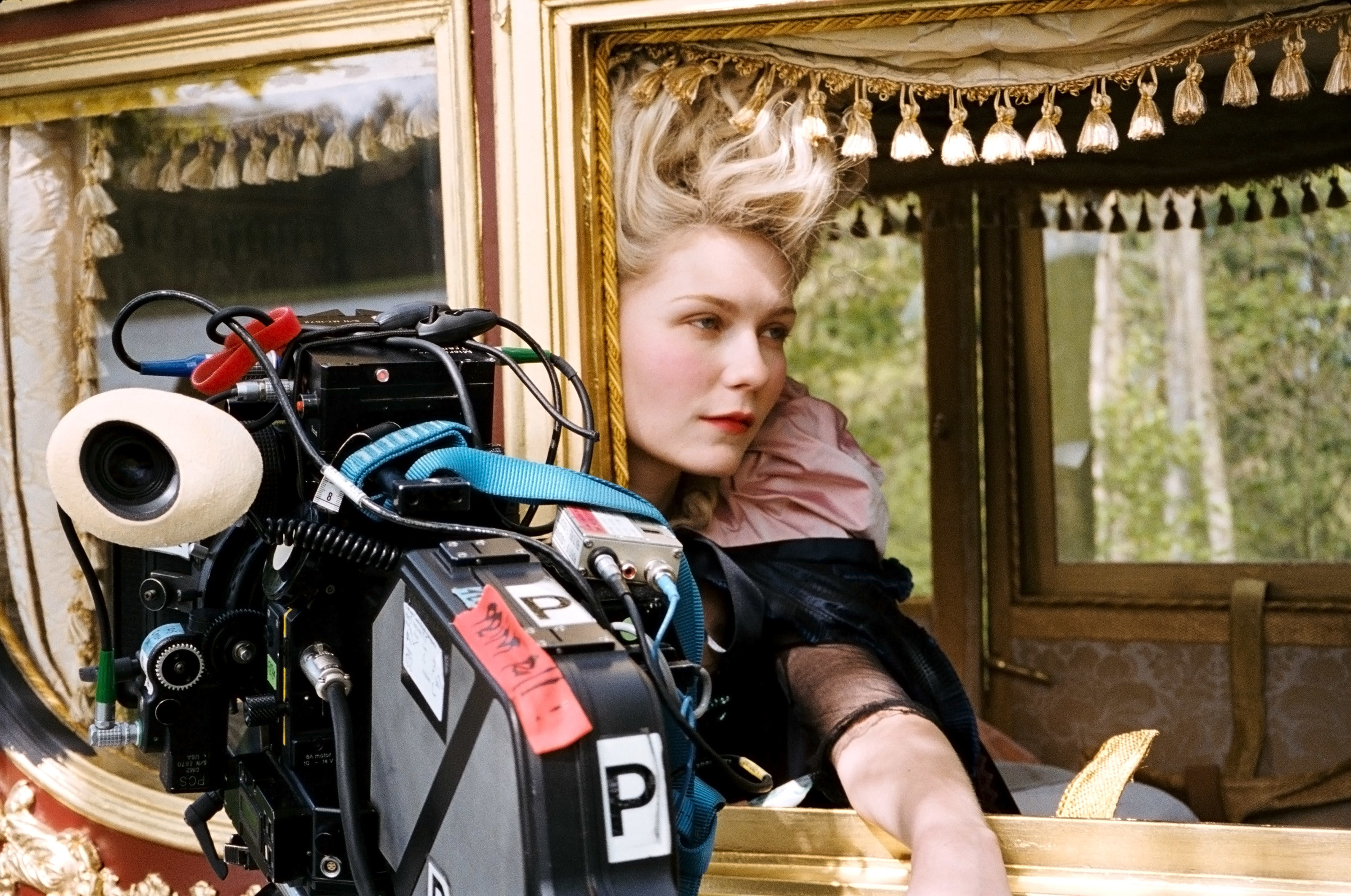 Kirsten Dunst in a carriage next to a large camera