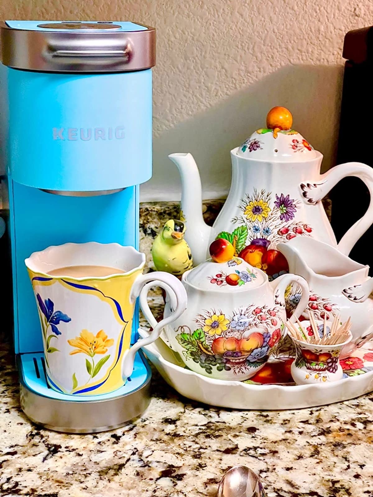 Reviewer image of blue Keurig with a colorful cup in it and a tea set next to it