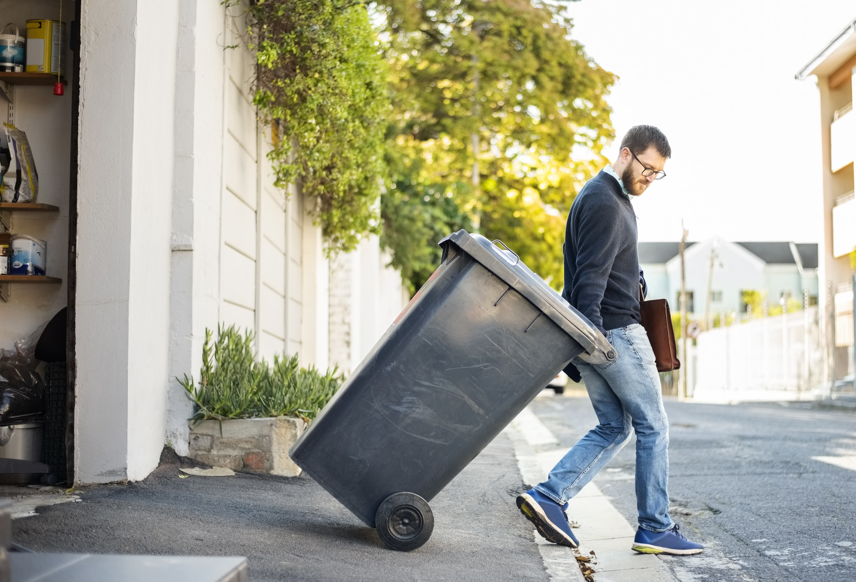man rolling out his garbage bin