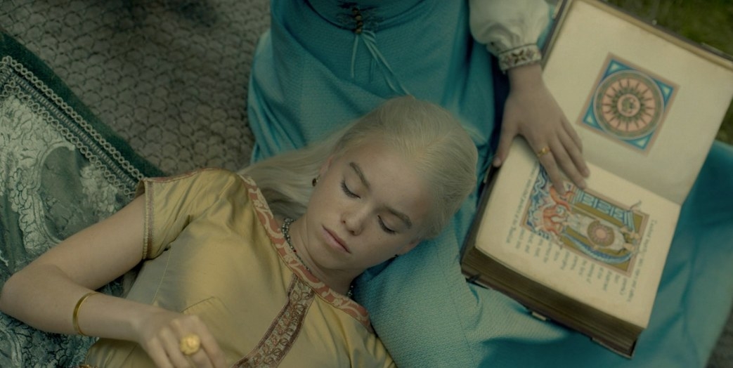 Rhaenyra lies in Alicent&#x27;s lap next to an illustrated book