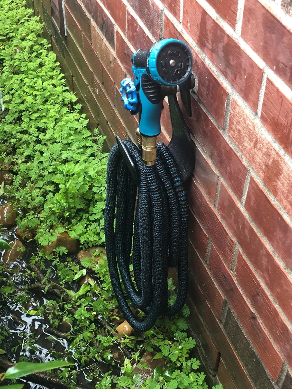 Reviewer&#x27;s hose coiled up on holder attached to brick side of house