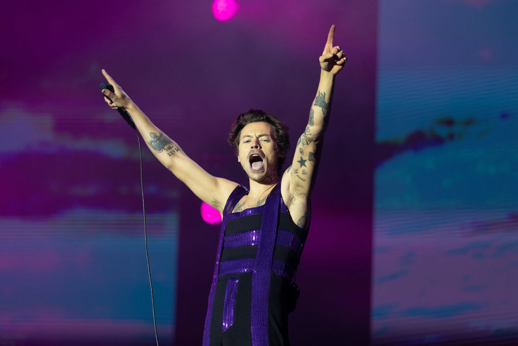 Harry onstage performing with his arms raised