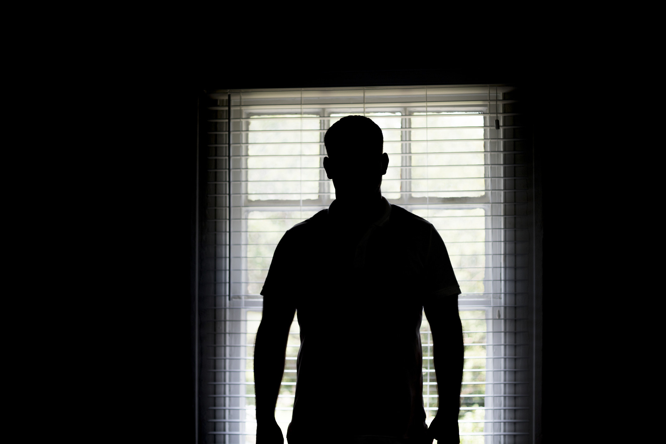 man standing in the shadows in a front of a window