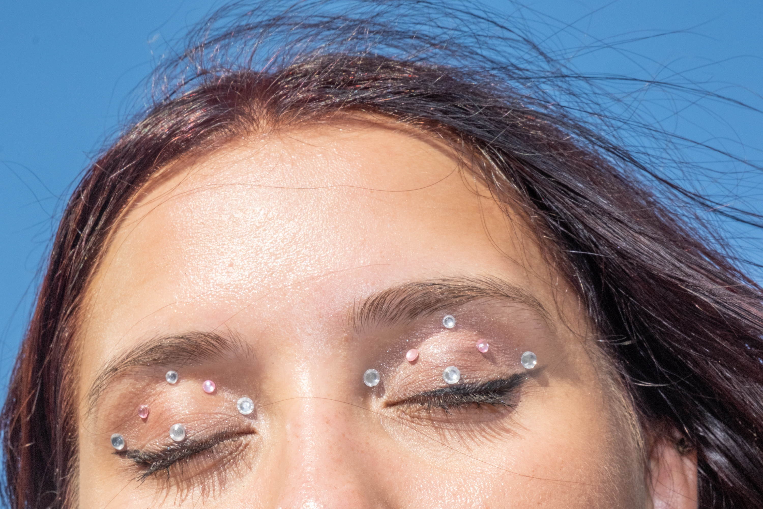 A woman shows her eye lids that are decorated with sequins