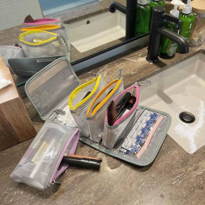 the organizer laid on a bathroom counter showing all the removable zippered pouches