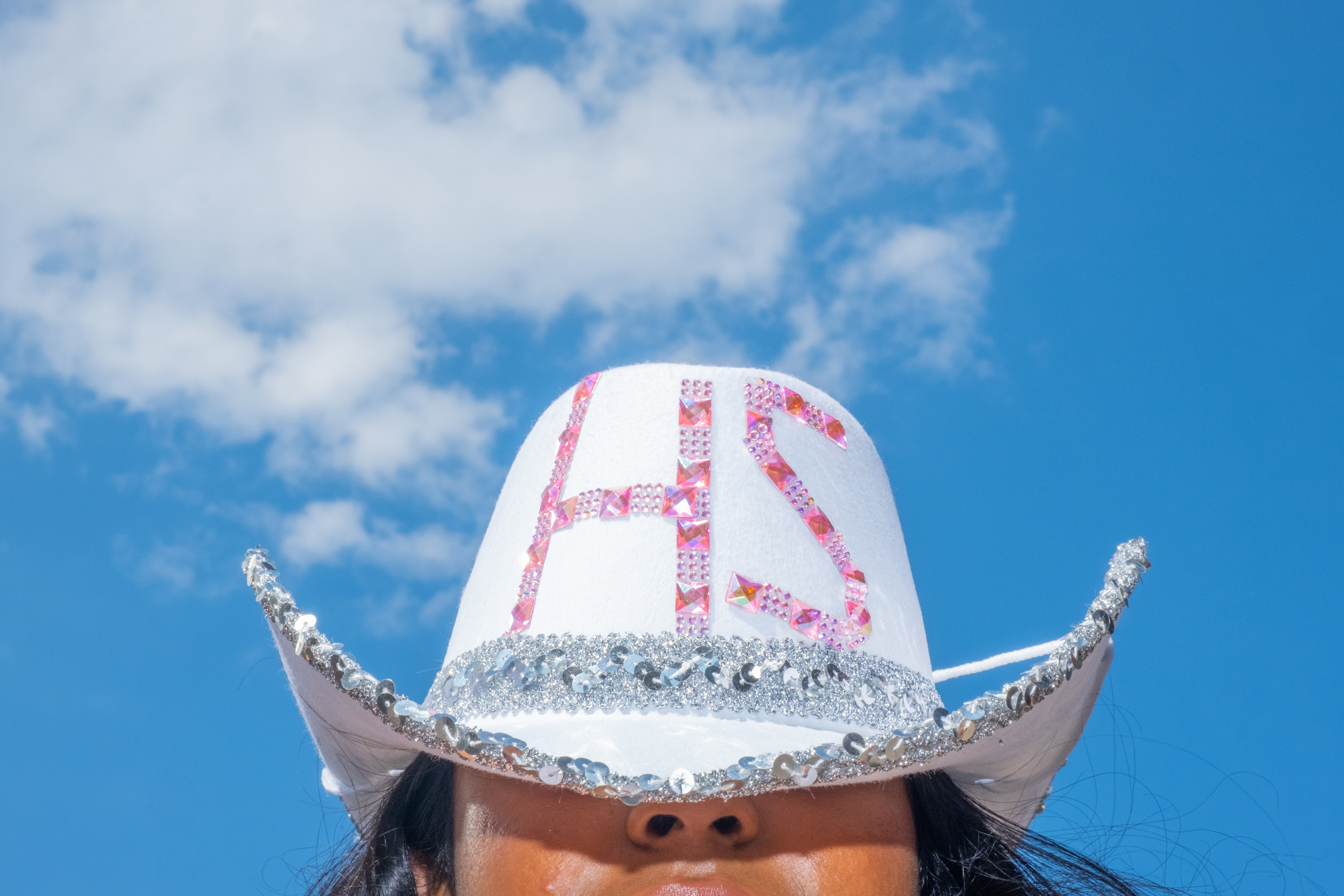 A woman wears a cowboy hat decorated with sequins and gemstones that spell &quot;HS&quot;