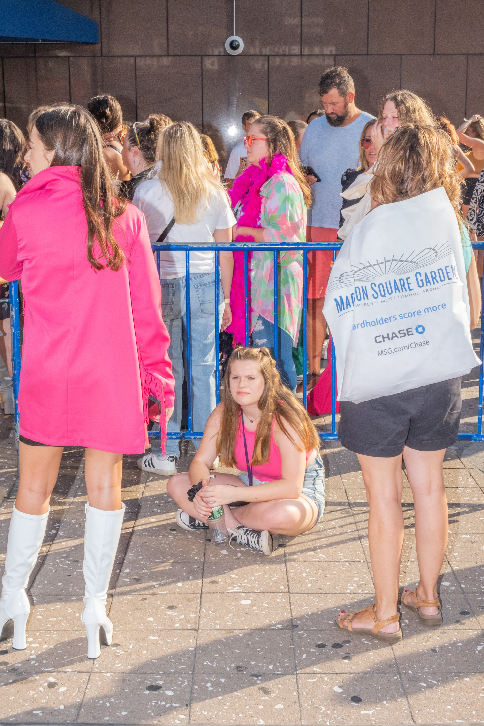 A woman sit on the ground, surrounded by Styles fans waiting to get into Madison Square Garden