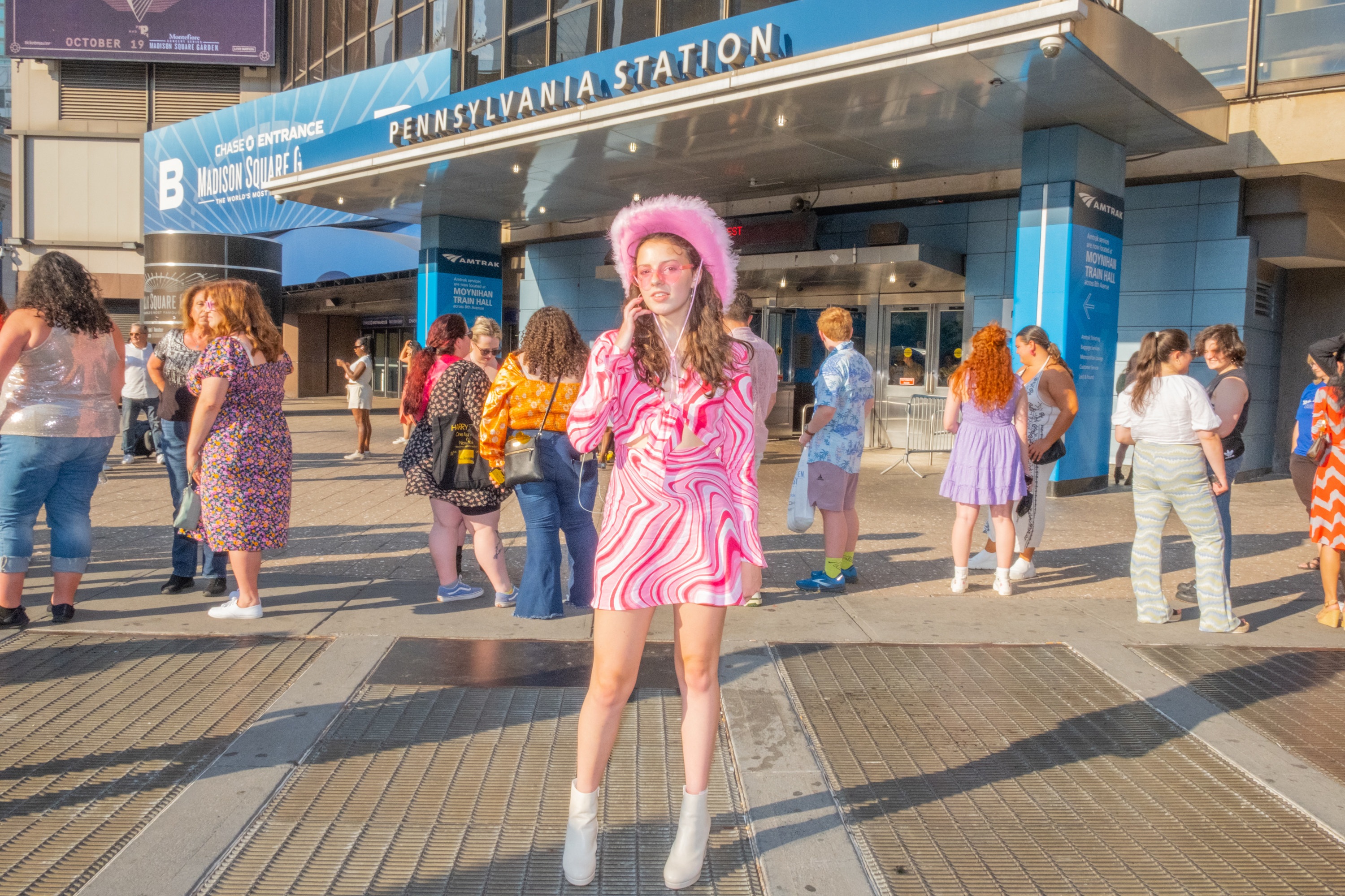 A woman wearing a vibrant outfit stands in front of the entrance to Pennsylvania Station