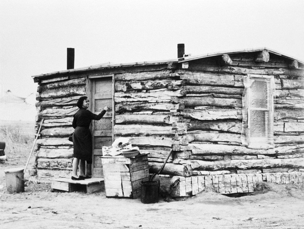 small log cabin with a woman knocking on the front door