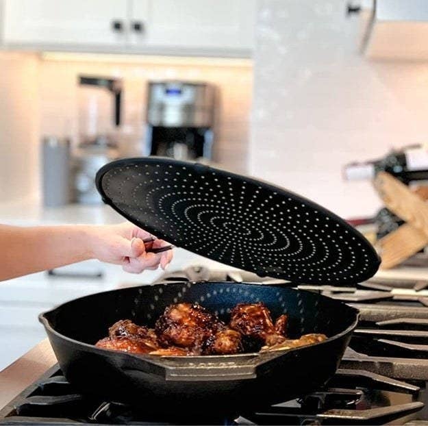 a person holding a splatter cover over a pan