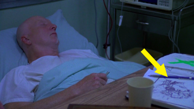 A man lies in a hospital bed with a bunch of drawings near him